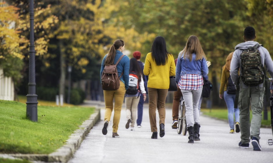 A group of students walking on a sidewalk.