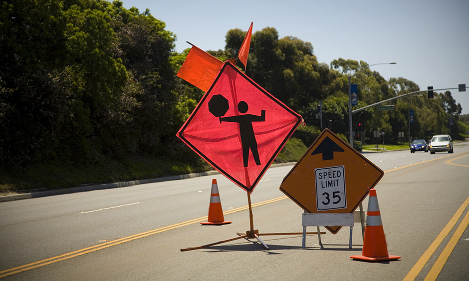 A road sign alerting drivers to a worker flagging traffic up ahead