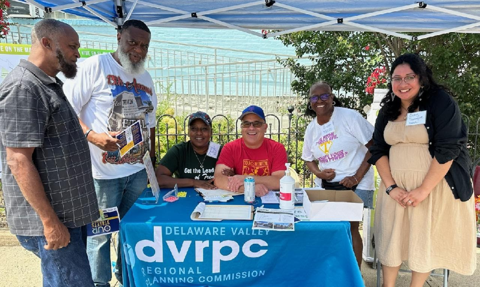 A group of volunteers sit at a registration table at a public engagement event.