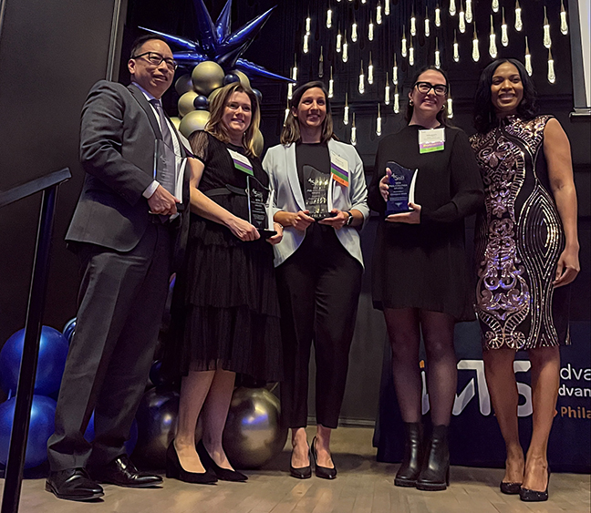 Five people pose with awards at an awards ceremony