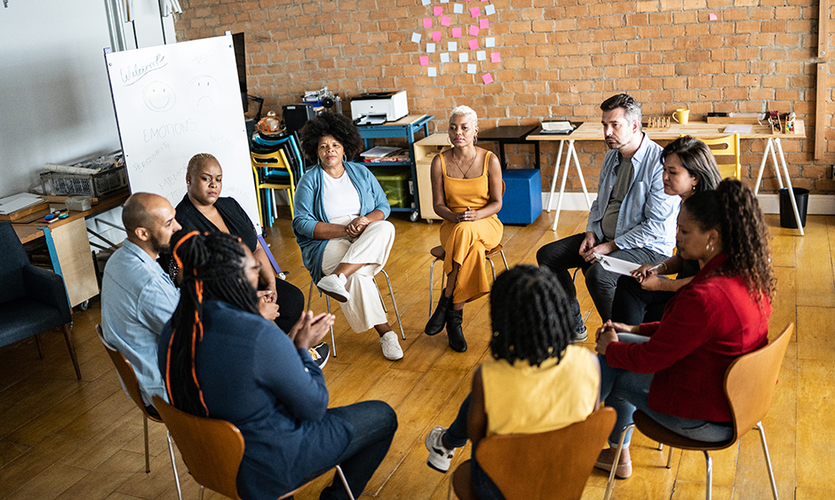 A group of people sit in a circle during a focus group conversation