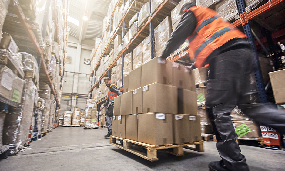 Workers moving boxes on a dolly in a warehouse