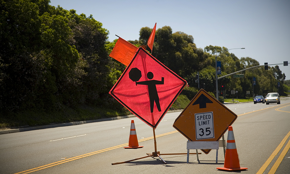 A road sign alerting drivers to a worker flagging traffic up ahead