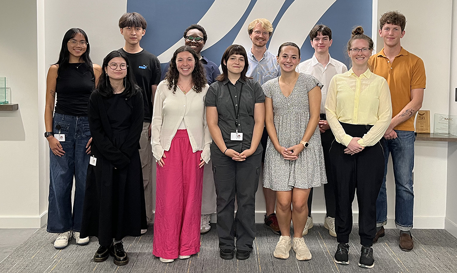A group of 11 people stand together for a photo