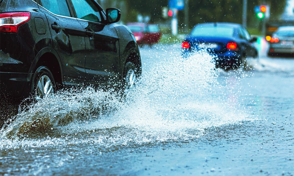Cars drive through a flooded road