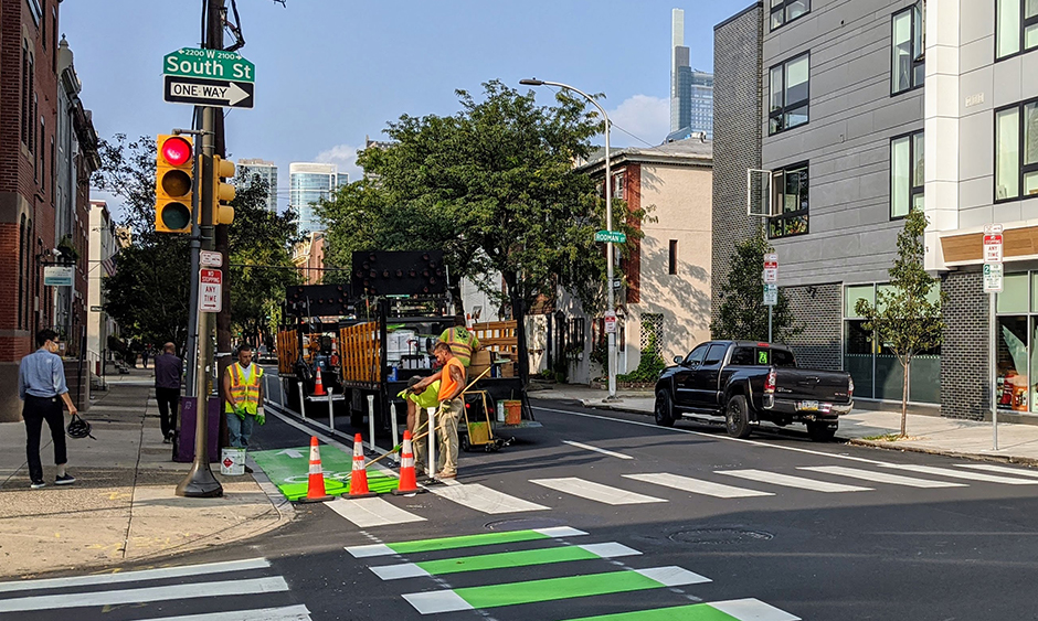 Workers paint a new bike lane on a road in Philadelphia
