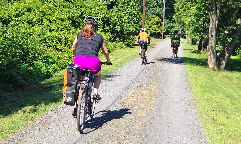 Three people ride bikes on a trail in a residential area