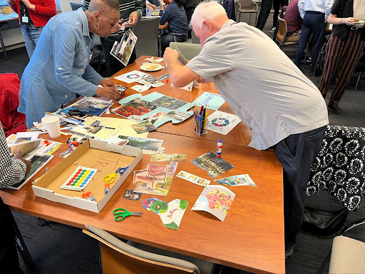 Two people work together on a collage during a public meeting