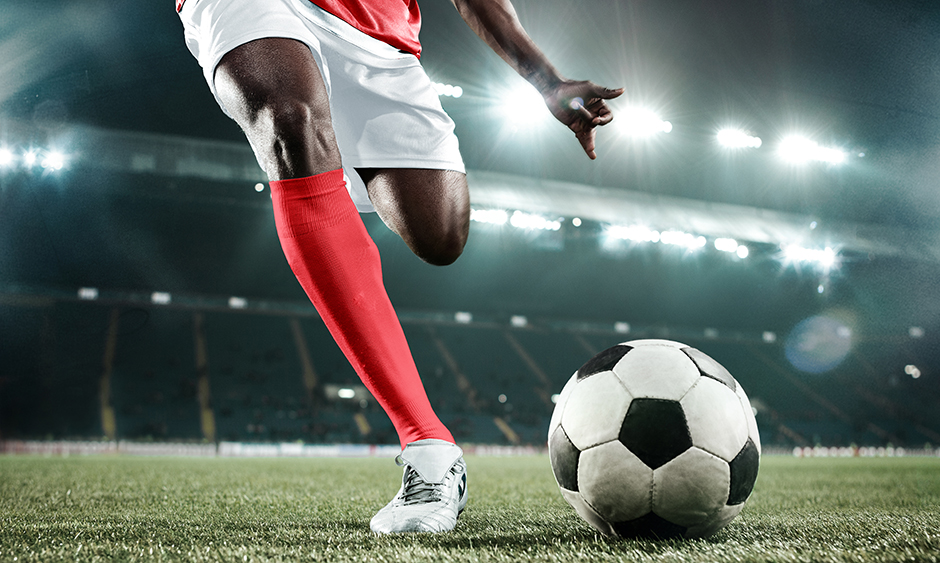 Lit up by stadium lights, a soccer player is about to kick the ball